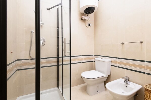 A bathroom with a glass-enclosed shower, a toilet, a bidet, and a sink.