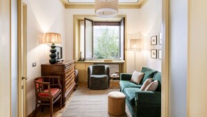 A compact living room with a sofa, chairs, a desk, and a window with a view. - Easylife - Classy abode in the Conciliazione area (Milano)