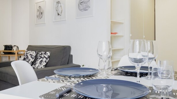 Een eethoek met een tafel gedekt voor vier personen, inclusief borden, bestek en glazen.