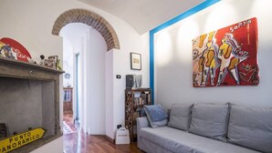 A living room with a grey sofa, a bookshelf, a painting, and a wooden floor. - Easylife - Stunning apt in the design district (Milano)