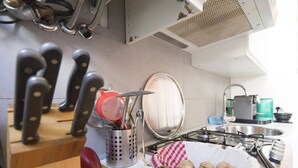 A kitchen with a wooden cutting board, a colander, a basket of nuts, and a stainless steel sink. - Easylife - Stunning apt in the design district (Milano)