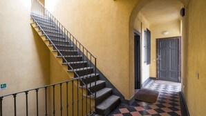 A staircase with a black railing leading to a landing with a checkered floor pattern. - Easylife - Stunning apt in the design district (Milano)