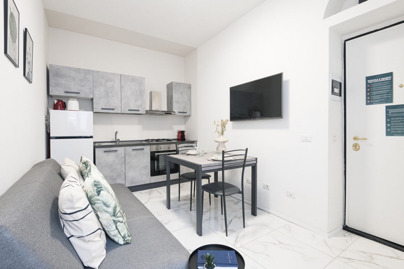 A compact living space with a kitchenette, a dining area, and a sofa.