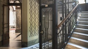 A staircase with a metal railing, a patterned wall, and a door with a sign. - Classic Studio in Washington area by Easylife (Milano)
