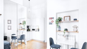 A modern kitchen with white cabinets, a microwave, and a dining area with a white table and chairs. - Classic Studio in Washington area by Easylife (Milano)