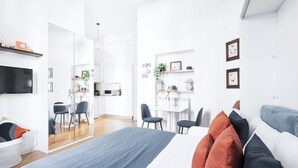 A modern, well-lit bedroom with a large bed, a desk, and a seating area. - Classic Studio in Washington area by Easylife (Milano)