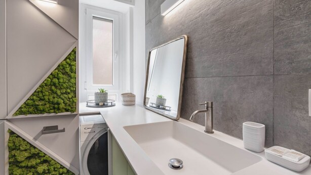 Une salle de bain moderne avec un grand miroir, un lavabo et un lave-linge.