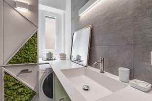 Un baño moderno con un espejo grande, un lavabo y una lavadora.