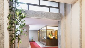 A lobby with a red carpet, a reception desk, and a potted plant. - Easylife - Charming flat 5 min from Centrale (Milano)