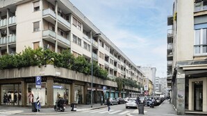 A multi-story building with balconies, storefronts, and parked cars. - Easylife - Charming flat 5 min from Centrale (Milano)
