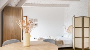 A modern bedroom with a bed, a bedside table with a vase of dried plants, and a wooden partition. - Easylife - Exclusive penthouse with panoramic view (Milano)