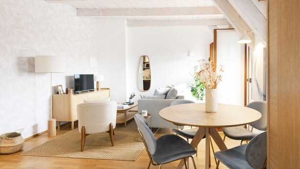 A modern living room with a round wooden table, grey sofa, and a TV on a wooden stand. - Easylife - Exclusive penthouse with panoramic view (Milano)