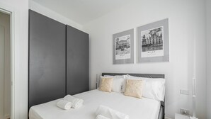 Een moderne hotelkamer met een groot bed, twee ingelijste foto's aan de muur en een nachtkastje met een lamp.