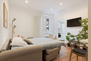 A modern hotel room with a bed, a desk, a chair, a TV, and a plant. - Easylife - Amazing studio with botanic touch in the Center (Milano)