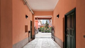 Un pasillo con piso de baldosas que lleva a una puerta verde y una ventana.