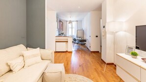 Una sala de estar moderna con un sofá, un comedor con una mesa y sillas, y una cocina al fondo.