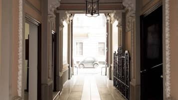 A hallway with a car parked outside, leading to a black door.