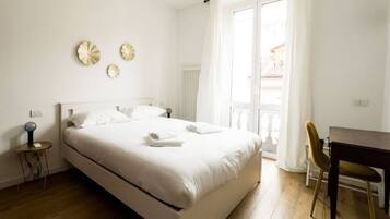 A bedroom with a bed, a bedside table, a chair, and a window with curtains.