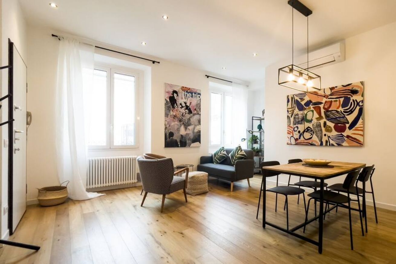A modern living room with a sofa, dining table, and artwork on the walls.