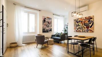 A modern living room with a sofa, dining table, and artwork on the walls.