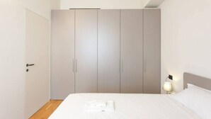 A bedroom with a bed, a nightstand, a lamp, and a wardrobe.