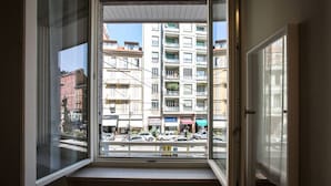 A window with a view of a multi-story building with balconies and a street below.