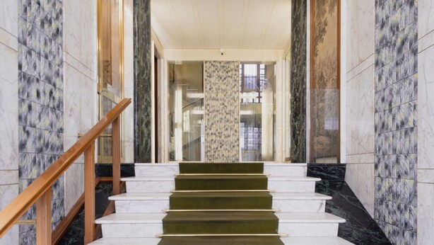 A grand staircase with marble steps and wooden handrails, leading to a glass elevator. - Easylife - Gorgeous flat in the Design District (Milano)