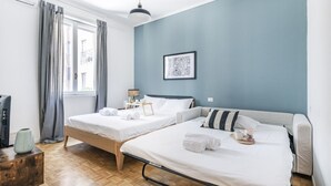 A bedroom with two beds, a bedside table, a lamp, and a framed picture on the wall. - Easylife - Gorgeous flat in the Design District (Milano)