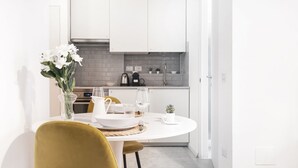 A modern kitchen with white cabinets, a dining table set with white plates, and a vase of flowers. - Easylife - Gorgeous flat in the Design District (Milano)