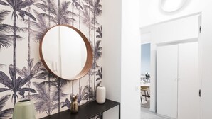 A hallway with a black console table, a round mirror, and a decorative vase. A white door is visible in the background. - Easylife - Gorgeous flat in the Design District (Milano)