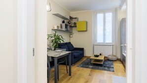 Een moderne woonkamer met een eethoek, een blauwe bank, een salontafel en een potplant.