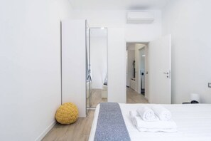 A modern hotel room with a bed, a mirror, a wardrobe, and a bathroom visible through an open door. - Easylife - Cozy and chic flat in Risorgimento area (Milano)