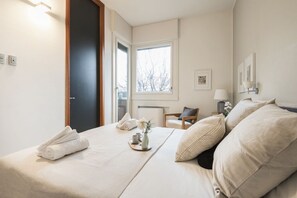 Une chambre d’hôtel avec un lit, une chaise, une fenêtre et une porte.