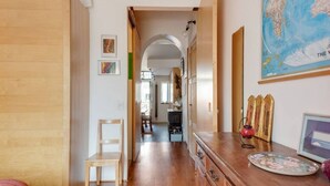 A hallway with wooden flooring, a wooden chair, a dresser with a decorative plate, and a map on the wall. - Easylife - Attico Duplex Chinatown (Milano)