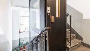 A black door with a small window and a metal railing leading to a staircase. - Easylife - Cozy studio apartment in Porta Venezia (Milano)