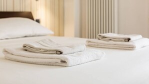 A neatly made bed with folded white towels and a wooden headboard.