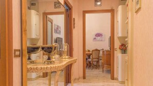 A hallway with a marble floor leading to a dining area with a wooden table and chairs. - Easylife - Elegant and cozy apt in Città Studi (Milano)