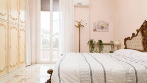 A bedroom with a large bed, a wardrobe, a floor lamp, and a window with curtains. - Easylife - Elegant and cozy apt in Città Studi (Milano)
