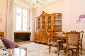 Ein Zimmer mit einem großen Holzkabinett, einem Esstisch mit Stühlen und einer Kristallleuchter.