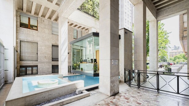 A modern indoor pool area with a glass enclosure, stone walls, and a tiled floor. - Easylife - Elegant studio apartment in Corso Magenta (Milano)