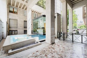 Un espace piscine intérieur moderne, doté d’une paroi vitrée, de murs en pierre et d’un sol carrelé.