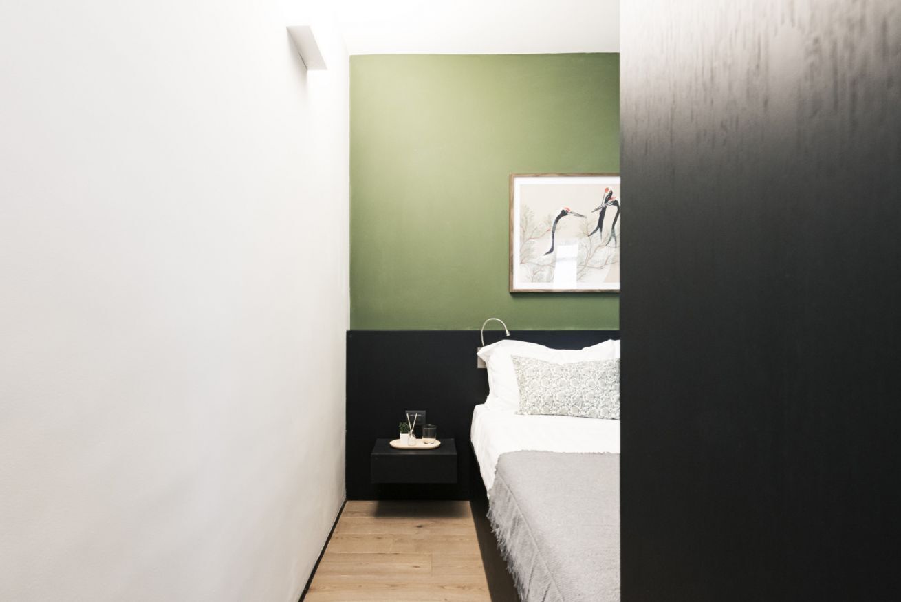 A bedroom with a bed, a nightstand, and a framed artwork on the wall.