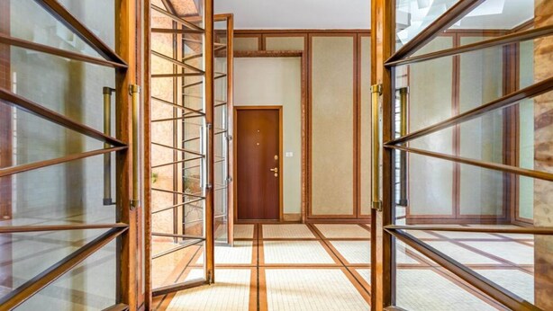 Un interior japonés tradicional con suelo de esteras de tatami, puertas correderas y una puerta de madera en el centro.
