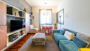 Una sala moderna con televisor de pantalla plana, un sofá, una mesa de comedor con sillas y una estantería.