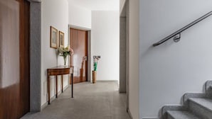 Un couloir avec une porte en bois, une console surmontée d’un vase et un escalier.