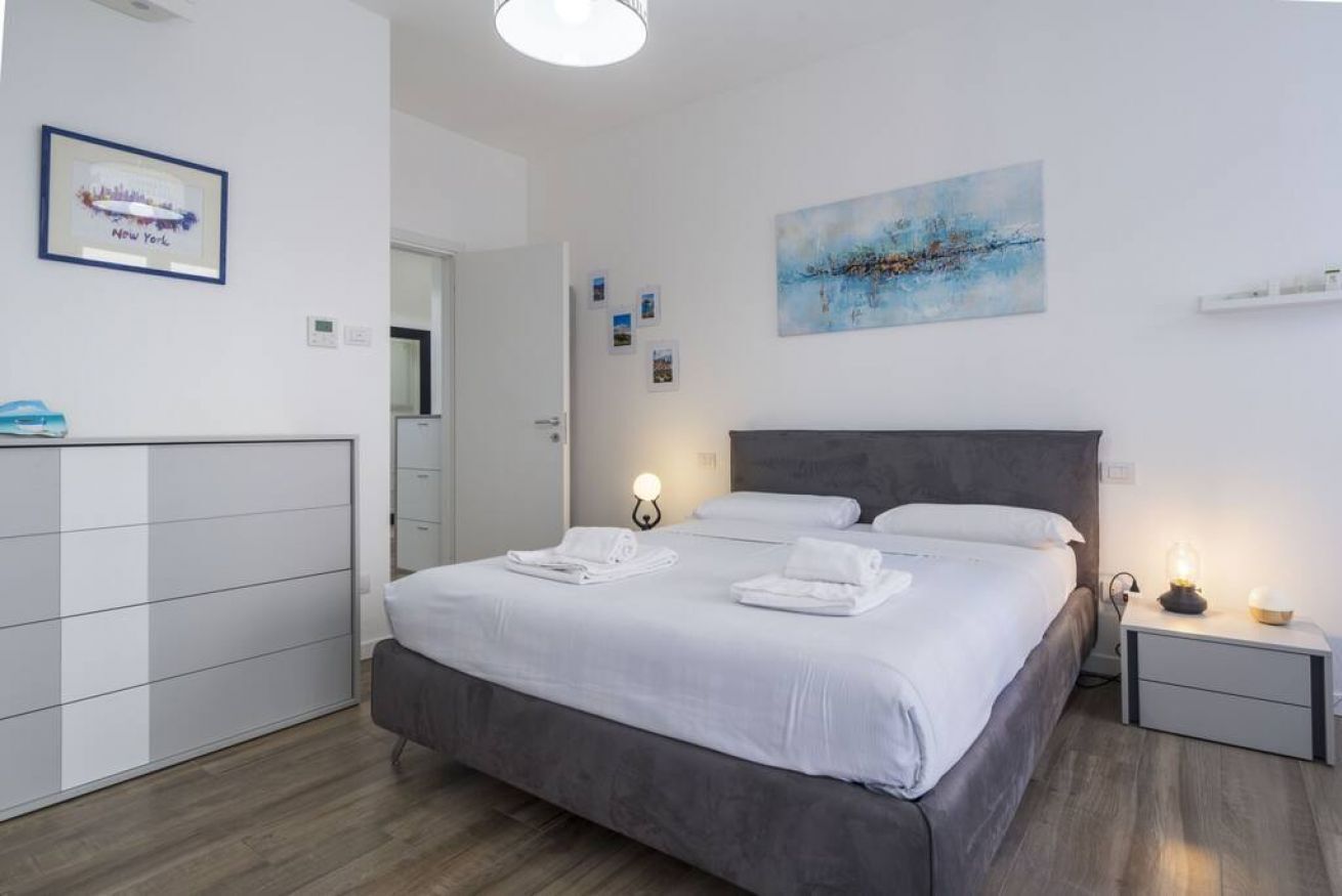 Een moderne hotelkamer met een groot bed, bedlampen, een garderobe en kunstwerken aan de muur.