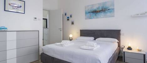 Een moderne hotelkamer met een groot bed, bedlampen, een garderobe en kunstwerken aan de muur.