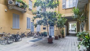 Une cour intérieure agrémentée de plantes en pot, de vélos et d’un arbre.