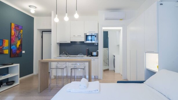 Une chambre d’hôtel moderne équipée d’un lit, d’une petite kitchenette et d’un coin repas.
