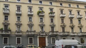 Un immeuble à plusieurs étages doté de balcons, d’une entrée principale et d’un fourgon stationné à proximité.